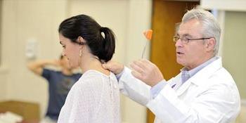 A chiropractic professor teaching a student at University of Bridgeport
